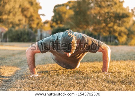 Sports and yoga. A man in sportswear push-ups on the grass