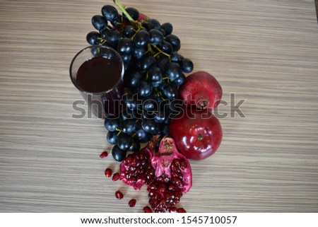 The best stock photo of red juice with fruits, pomegranate, grapes and yalok on a wooden table. Healthy eating.
