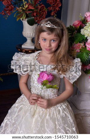 young princess in a white dress and a diadem in her hair among flowers