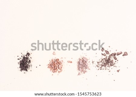 Scattered eyeshadows of beige and brown shades on a light background. The concept of decorative cosmetics, makeup. Minimalism. Copy space.