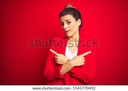 Young beautiful business woman standing over red isolated background Pointing to both sides with fingers, different direction disagree