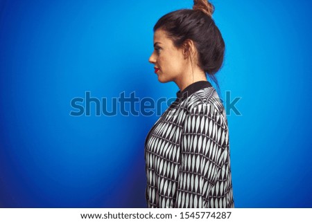 Young beautiful woman wearing a jacket standing over blue isolated background looking to side, relax profile pose with natural face with confident smile.