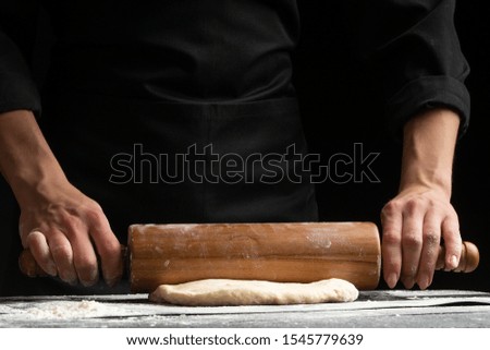 The chef cooks the dough under a rosquat press, for baking, bread, pizza, or pasta. on a black background