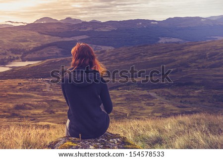 Woman sitting on mountain top and contemplating the sunset Royalty-Free Stock Photo #154578533