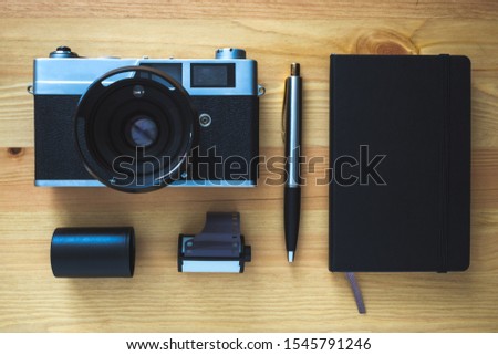 vintage camera, roll of film, pen and notebook on table