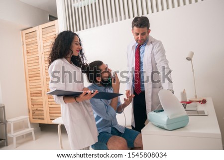 Patient hipster having an asthma attack at the doctors office with the nurse helping the diagnosis