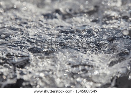 Texture of transparent ice from a melting river close-up on a bright sunny day. Abstract background