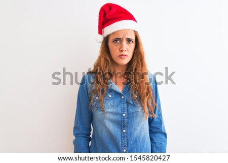 Young beautiful redhead woman wearing christmas hat over isolated background depressed and worry for distress, crying angry and afraid. Sad expression.