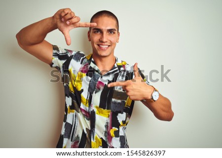 Young handsome man wearing summer shirt over white isolated background smiling making frame with hands and fingers with happy face. Creativity and photography concept.