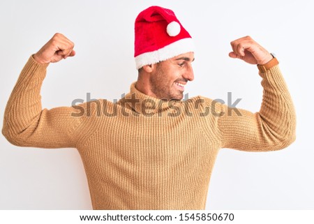 Young handsome man wearing christmas and turtleneck sweater over isolated background showing arms muscles smiling proud. Fitness concept.
