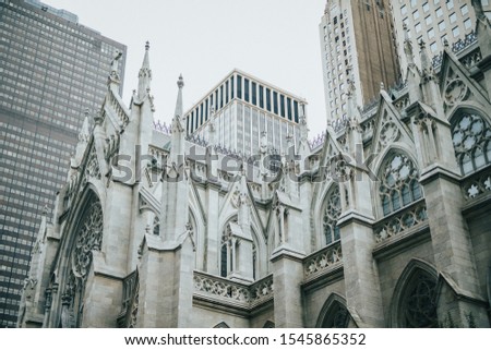 A low angle shot of a white gothic architecture building with modern buildings in the background