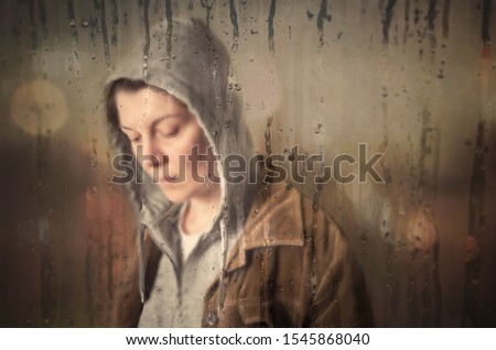 Depressed woman behind the wet window  Royalty-Free Stock Photo #1545868040