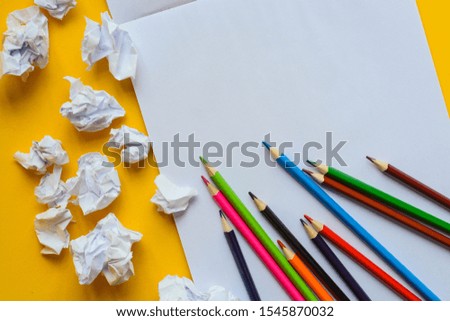 Colourful pencils on a white sheet of paper against yellow background. Creation concept represented and space for text 