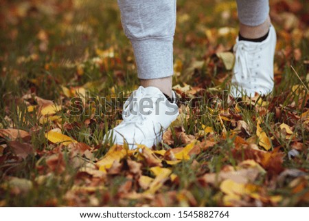 girl walks in the park through yellow foliage in casual clothes, autumn sport concept outdoors