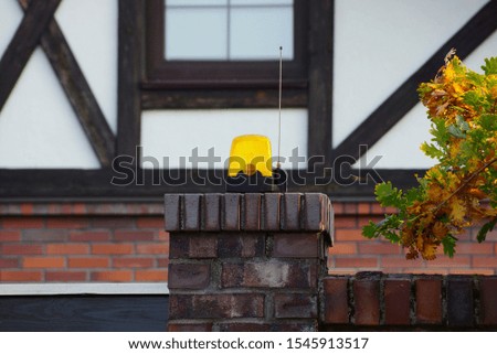 one yellow signal light hanging on a brown brick fence