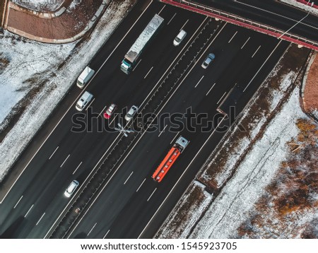 Aerial view of country road and bridge, road traffic, snow-covered forests and fields, winter. Russia, St. Petersburg