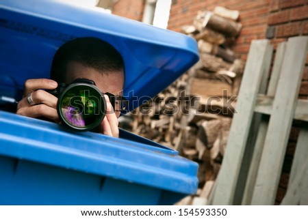 Paparazzi hiding in a blue garbage bin to take pictures