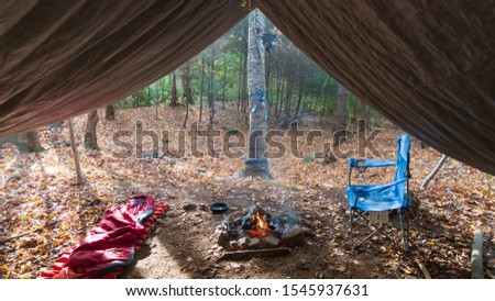 Primitive Tarp Shelter with campfire and fairy lights. Survival Bushcraft campsite setup in the Blue Ridge Mountains near Asheville. Camping During autumn / fall season.