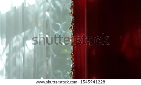 Beautiful red and white curtains on the window on a clear sunny day. sunny glare on the beads of the decor.