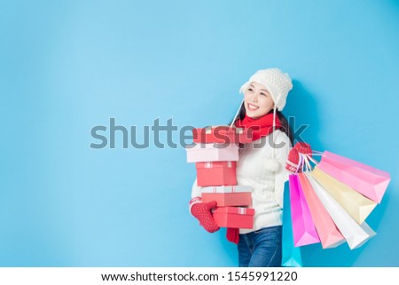 asian woman wear winter clothes with sopping bags and show something isolated on blue background