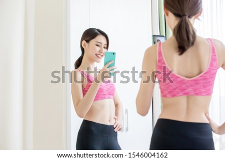 asian woman take selfie in front of mirror with sport wear happily