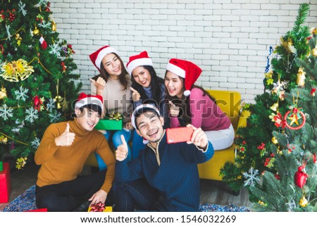 Group of asian friends taking selfie with friend together by smartphone at home during chrismas eve party or New year celebrate party. Happy winter Xmas and Happy new year party concept