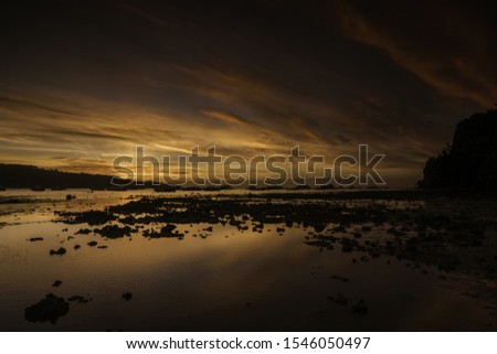 A breathtaking scenery of the beautiful colorful sky reflected in the lake covered with moss during sunset