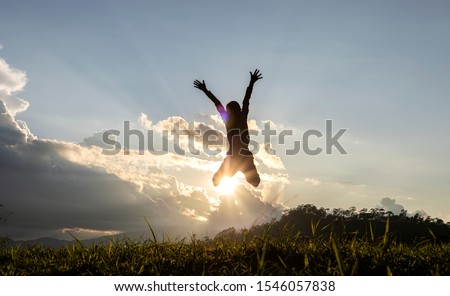 Silhouette of happy child jumping playing on mountain at sunset or sunrise