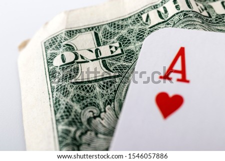 Ace of hearts, playing card close up lying on top of United States Currency. Gambling, winning concept. Gambling entertainment. Play games of chance for money.