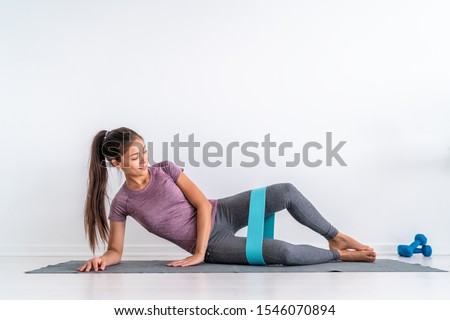 Resistance band clamshell leg workout hip abduction wide loop resistance booty circle bands toning inner and outer thighs, hamstring muscles. Asian fit girl training at home. Royalty-Free Stock Photo #1546070894
