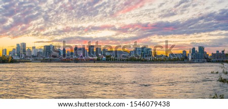 Panoramic landscape of downtown Montreal. View of Saint Lawrence river. Sunset behind Montreal and Mount Royal. Montreal skyline with skyscrapers in the foreground. Pink clouds and orange background.