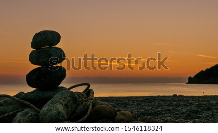 Beach stone fireplace with rope at sunrise. Sea water with rocks in the background. Vlychada Beach Peloponnese Greece.