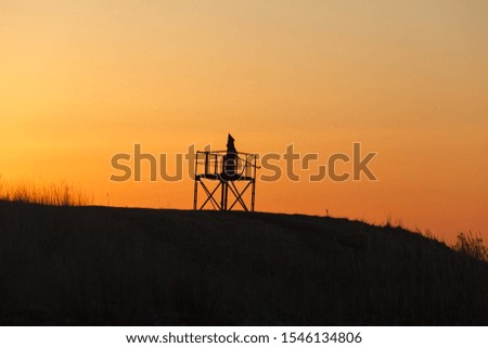 Silhouettes of the monk on the tower at sunset