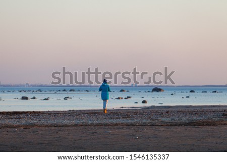 Woman is walking along the sea coast at sunset