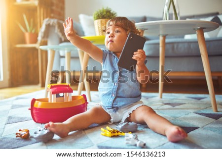 Beautiful toddler child girl sitting on the carpet playing with smartphone