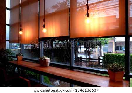 View of blind glass window decoration with lambing hanging on ceiling, Picture of curtains in room with glass and decorated with light bulbs while  raining.