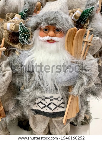 Santa Claus as Toy in gray suit costume in a cap and gold-rimmed glasses with a blush on the cheeks and ski carry gifts sale, market, disposal, realization in the shop, supermarket