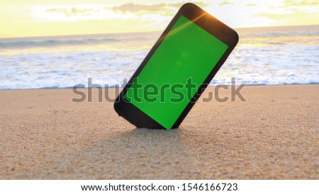 The phone has a green screen on the beach.