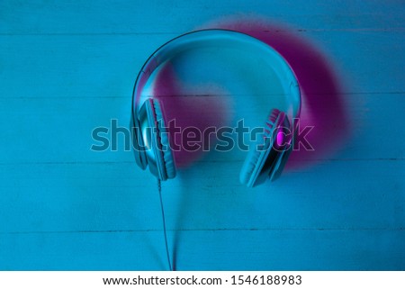 Top view of set of gadgets in purple neon light and blue background. Headphones on wooden table. Copyspace for your advertising. Tech, modern, gadgets.