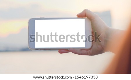 Hand of woman holding smartphone horizontal on outdoor sea city background