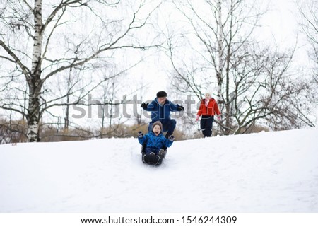 Children in the park in winter. Kids play with snow on the playground. They sculpt snowmen and slide down hills.