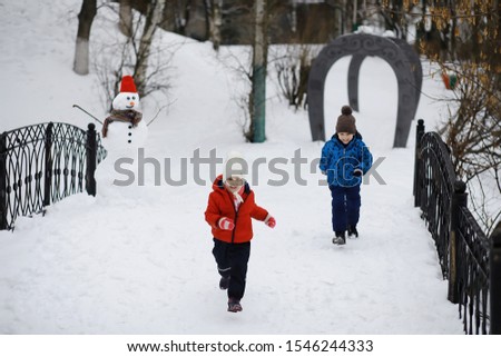 Children in the park in winter. Kids play with snow on the playground. They sculpt snowmen and slide down hills.