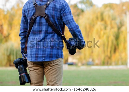 Professional photographer in action with two cameras on a shoulder straps.