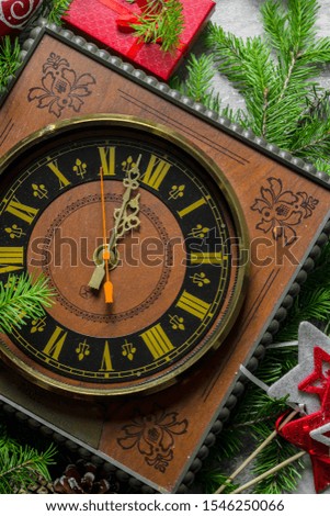 Christmas clock with red gift box and fir branches. On rustic background