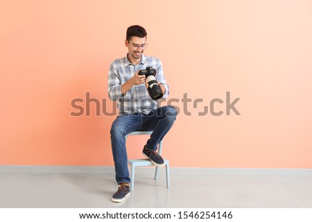 Young male photographer near color wall