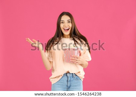 Surprised woman with popcorn on color background