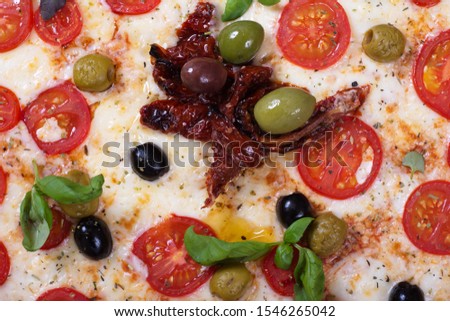 pizza with tomatoes, peppers and sausage lies next to spices on a dark background