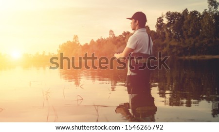 Man fishing  in the lake at sunset.
