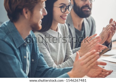 Young people working together at office having business meeting clapping to successful presentation close-up smiling cheerful