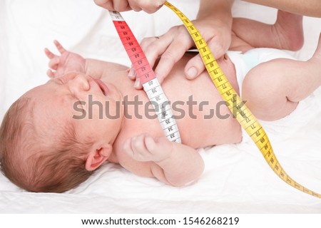 Pediatrician examines two week old baby. Doctor using measurement tape checking newborn's chest size. Newborn check-up concept Royalty-Free Stock Photo #1546268219